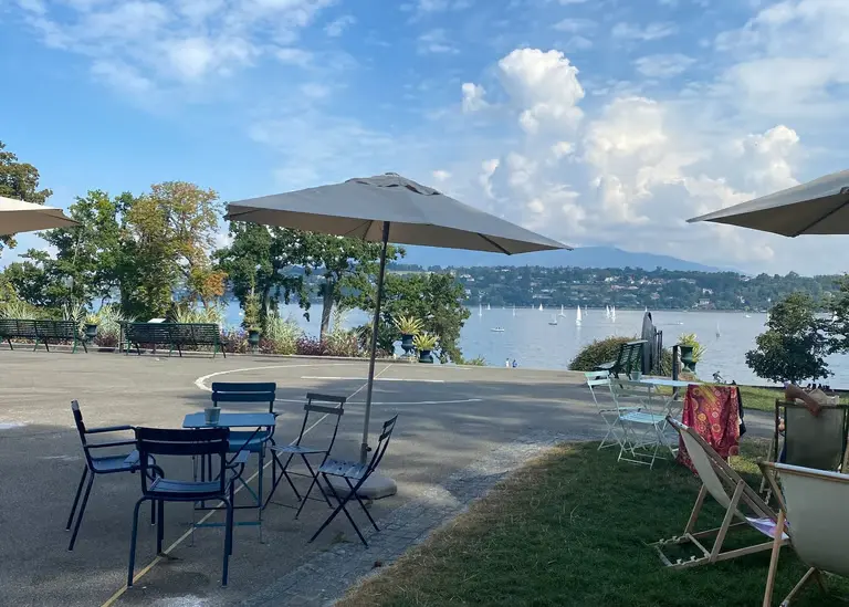 Lake Geneva terrace view with outdoor dining tables and sailboats - professional translation services in Geneva